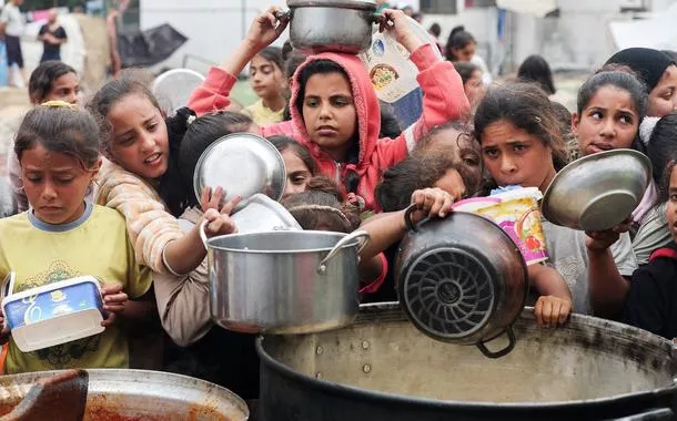 Palestinos aguardam para receber comida preparada por uma cozinha comunitária, em Nuseirat, Faixa de Gaza
08/04/2025
