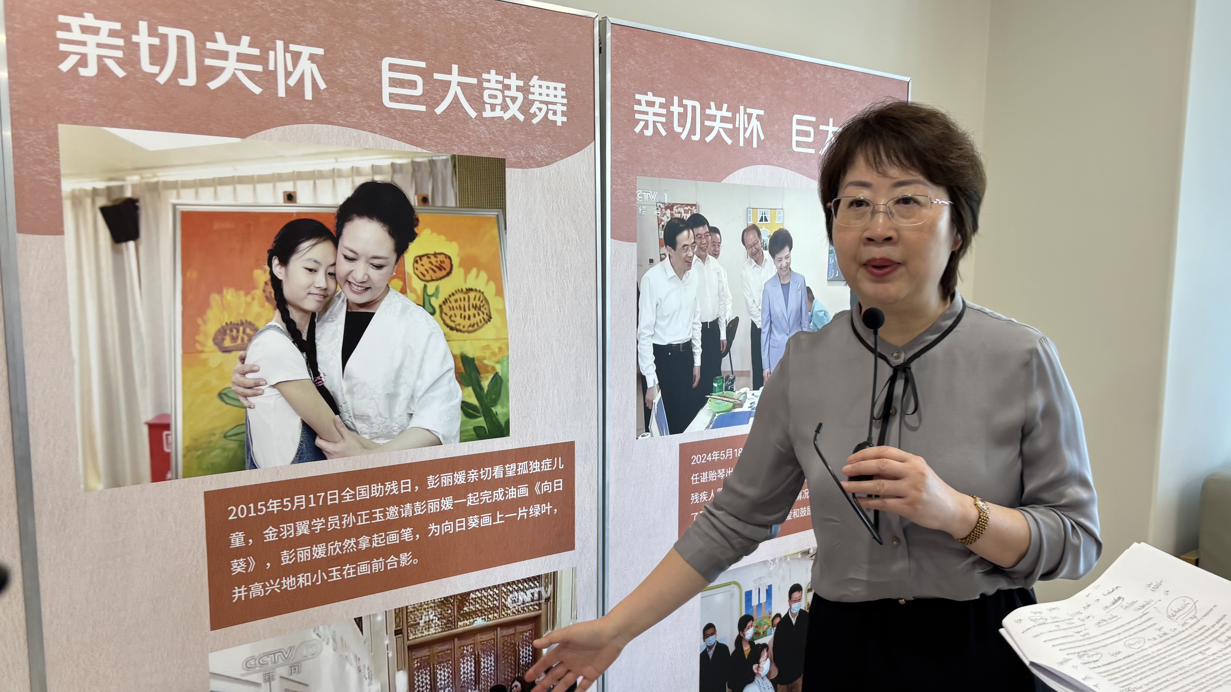 A fundadora Zhang Jun Ru exibe, orgulhosamente, o registro do dia em que a primeira-dama da China, Peng Liyuan, ajudou a jovem Xiao Yu, de 16 anos, diagnosticada com autismo e aluna do Centro, a pintar uma tela intitulada Girassóis.