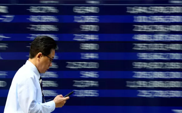 Um homem passa por uma tela eletrônica exibindo um quadro de cotações de ações em Tóquio, Japão, em 15 de abril de 2025