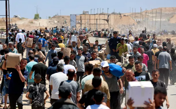 Palestinos carregam suprimentos de ajuda que receberam da Fundação Humanitária de Gaza, apoiada pelos EUA, no centro da Faixa de Gaza, em 29 de maio de 2025
