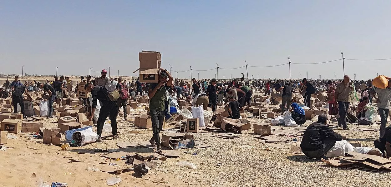 Palestinos coletam restos de suprimentos de ajuda da Fundação Humanitária de Gaza, apoiada pelos EUA