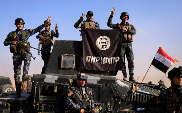 Membros da polícia federal posam com uma bandeira do Estado Islâmico (EI) em uma rua de Albu Saif, cidade retomada do Estado Islâmico, ao sul de Mosul, Iraque, em 22 de fevereiro de 2017