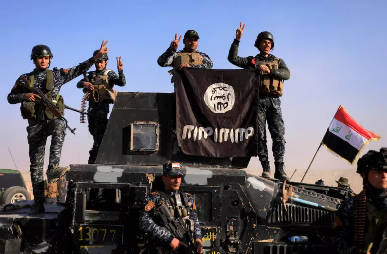 Membros da polícia federal posam com uma bandeira do Estado Islâmico (EI) em uma rua de Albu Saif, cidade retomada do Estado Islâmico, ao sul de Mosul, Iraque, em 22 de fevereiro de 2017