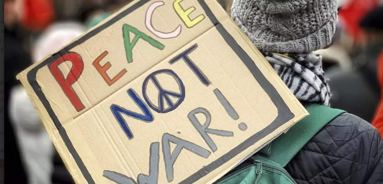 "Paz, e não guerra", diz cartaz de manifestante, na tradução livre do inglês