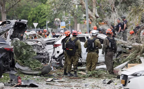 Equipes de resgate trabalham ao lado de veículos danificados em um local atingido por um ataque de mísseis do Irã contra Israel, em Rishon LeZion, Israel, em 14 de junho