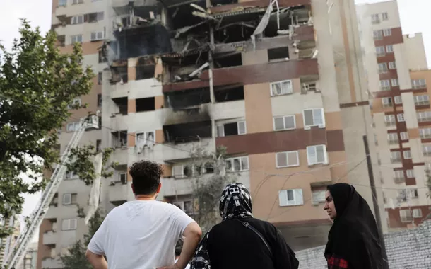 Pessoas observam um prédio danificado após ataques israelenses, em Teerã, Irã, em 13 de junho