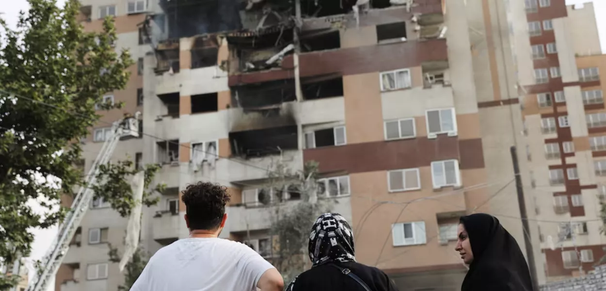 Pessoas observam um prédio danificado após ataques israelenses, em Teerã, Irã, em 13 de junho