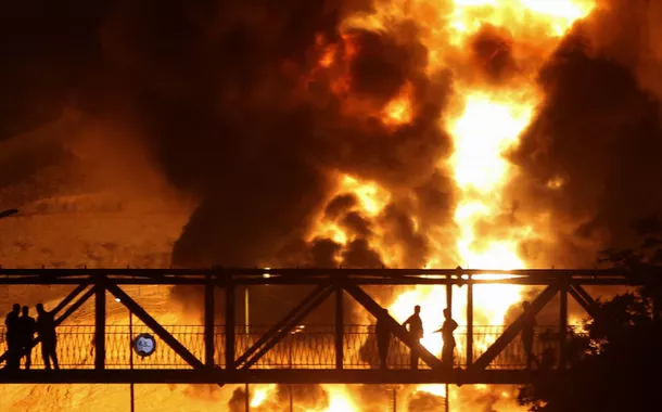 Pessoas observam de uma ponte as chamas de um ataque israelense subindo do depósito de petróleo de Sharan, após os ataques israelenses ao Irã, em Teerã, Irã, em 15 de junho de 2025