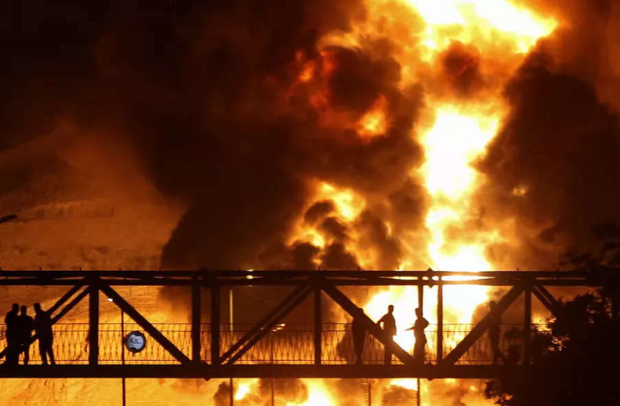 Pessoas observam de uma ponte as chamas de um ataque israelense subindo do depósito de petróleo de Sharan, após os ataques israelenses ao Irã, em Teerã, Irã, em 15 de junho de 2025
