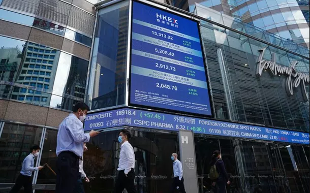 Pessoas passam por uma tela exibindo o índice de ações Hang Seng no distrito Central, em Hong Kong, China, em 25 de outubro de 2022