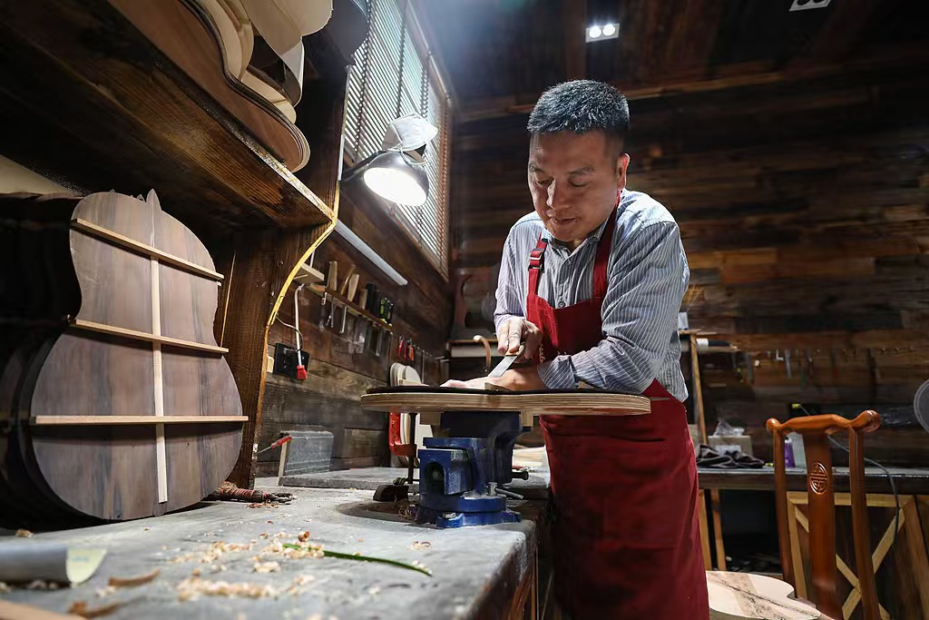 O luthier Zheng Weiyi, da Shenqu Guitars — uma das principais empresas de Zheng’an — confecciona guitarras personalizadas à mão, 18 de fevereiro de 2025
