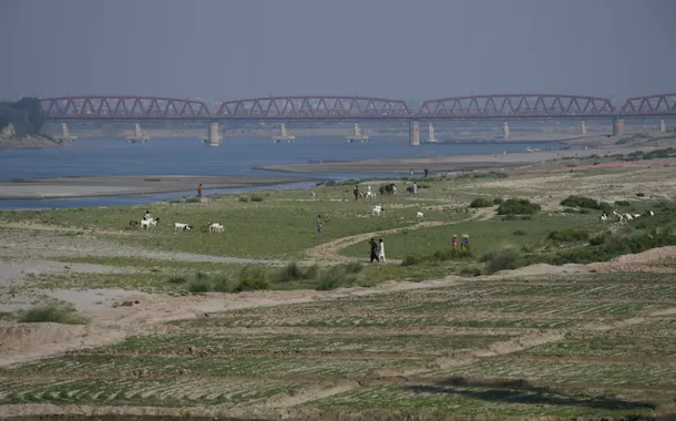 Pessoas caminham ao lado de uma terra cultivada no leito seco do rio Indo, em Hyderabad, Paquistão, em 25 de abril de 2025