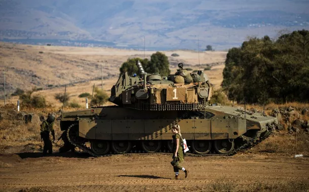 Um soldado israelense passa por um tanque em meio ao aumento das tensões entre Israel e o Líbano, visto da fronteira com o Líbano, no norte de Israel, em 14 de outubro de 2023