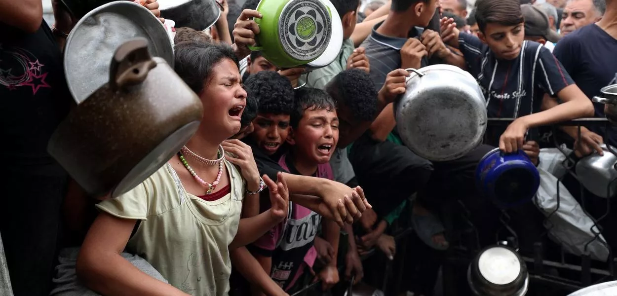 Crianças esperam em desespero entrega de comida em Beit Lahia, no norte da Faixa de Gaza, em meio ao genocídio cometido por Israel - 24/04/2025