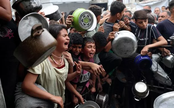 Crianças esperam em desespero entrega de comida em Beit Lahia, no norte da Faixa de Gaza, em meio ao genocídio cometido por Israel - 24/04/2025