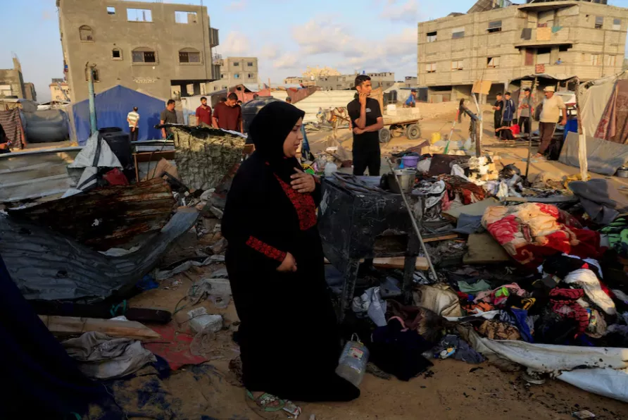 Palestinos inspecionam os danos no local de um ataque aéreo israelense durante a noite contra uma tenda que abrigava deslocados, em Khan Younis, no sul da Faixa de Gaza