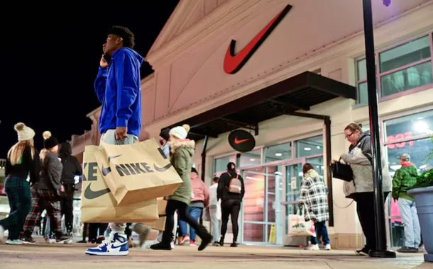 Um homem com bolsas da Nike fala ao telefone em frente a uma loja da Nike durante o início das vendas da Black Friday no The Outlet Shoppes of the Bluegrass em Simpsonville, Kentucky, EUA, em 26 de novembro de 2021
