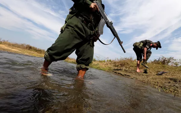 Um soldado do Exército de Independência de Kachin (KIA) calça os sapatos enquanto ele e seu companheiro cruzam um riacho em direção à linha de frente em Laiza, estado de Kachin, em 29 de janeiro de 2013