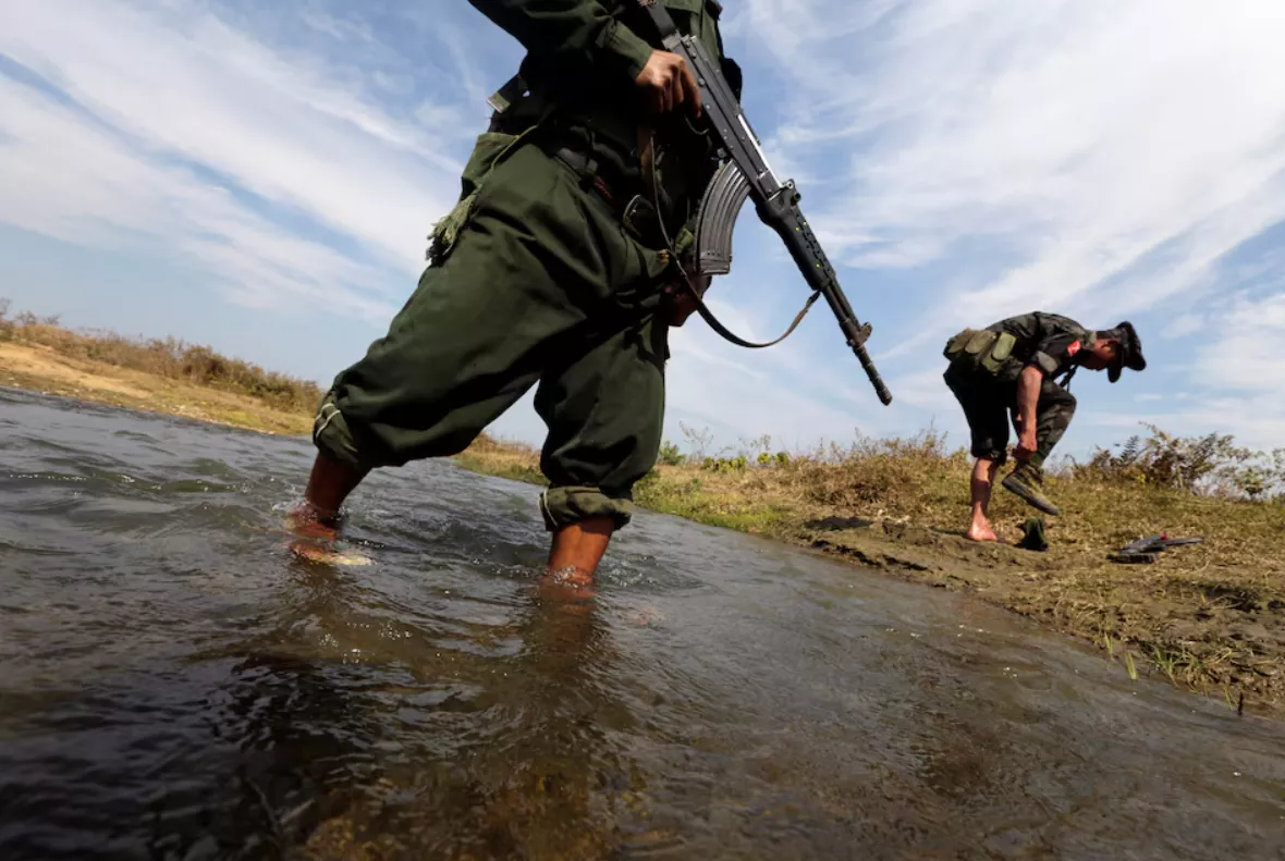 Um soldado do Exército de Independência de Kachin (KIA) calça os sapatos enquanto ele e seu companheiro cruzam um riacho em direção à linha de frente em Laiza, estado de Kachin, em 29 de janeiro de 2013