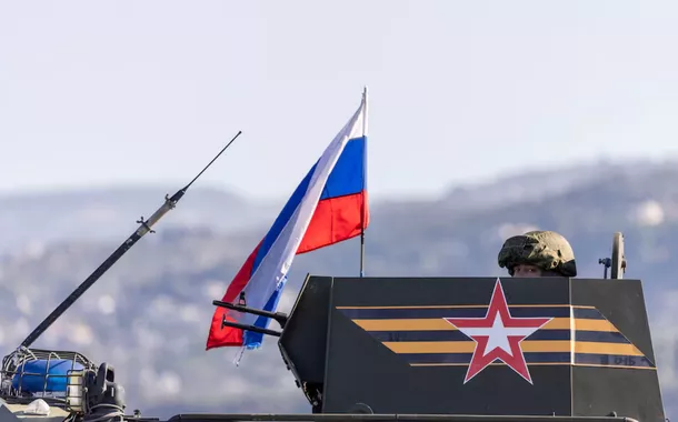 Um soldado russo viaja em um veículo de combate de infantaria, parte de um comboio militar russo em direção à base aérea de Hmeimim em Latakia, na costa da Síria, em 14 de dezembro de 2024