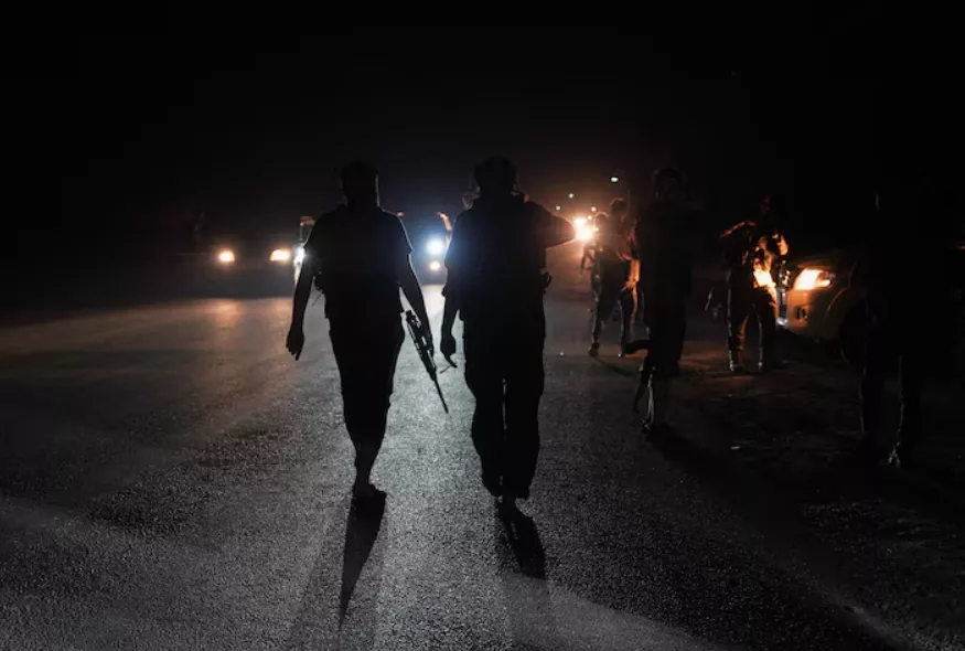 Membros das forças de segurança sírias caminham por uma estrada na zona rural de Sweida, enquanto veículos transportando outras forças de segurança sírias saem da cidade predominantemente drusa de Sweida, Síria, em 16 de julho de 2025