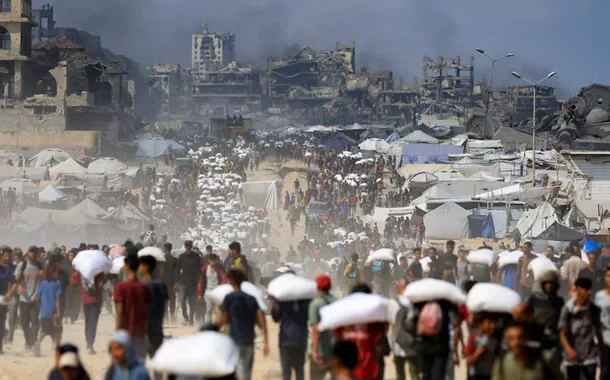 Palestinos se reúnem enquanto transportam suprimentos de ajuda que entraram em Gaza através de Israel, em meio a uma crise de fome, em Beit Lahia, no norte da Faixa de Gaza, em 20 de julho de 2025