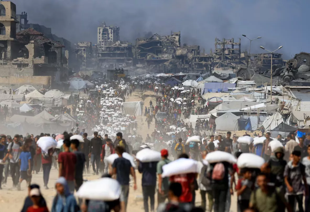 Palestinos se reúnem enquanto transportam suprimentos de ajuda que entraram em Gaza através de Israel, em meio a uma crise de fome, em Beit Lahia, no norte da Faixa de Gaza, em 20 de julho de 2025