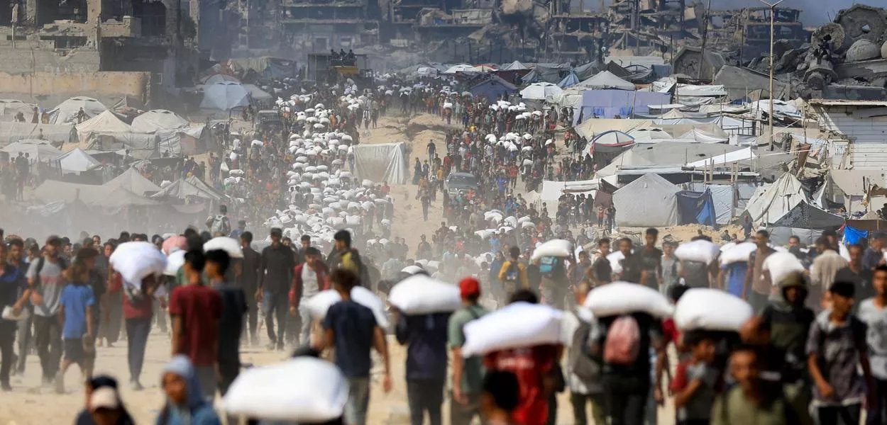 Palestinos transportam suprimentos humanitários em Beit Lahia, no norte da Faixa de Gaza - 20/07/2025