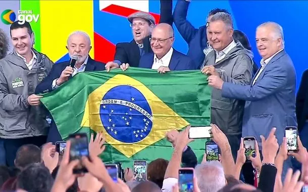 O presidente Luiz Inácio Lula da Silva, com o vice-presidente Geraldo Alckmin, seguram uma bandeira do Brasil, com ministros e outras figuras políticas, em Osasco, SP - 25/07/2025 