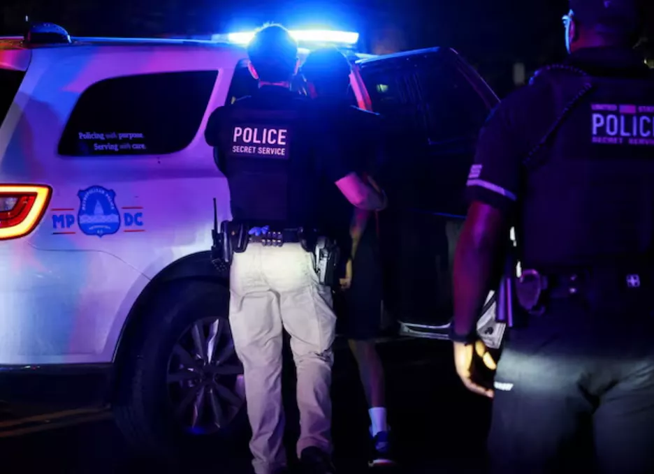 A polícia detém uma pessoa no bairro de Brightwood após o anúncio do presidente dos EUA, Donald Trump, da tomada federal do Departamento de Polícia Metropolitana sob o Home Rule Act e o envio da Guarda Nacional para auxiliar na prevenção de crimes na capital do país, em Washington, DC, EUA, em 14 de agosto de 2025