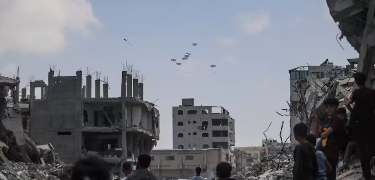 Palestinos observam pacotes de ajuda lançados de avião sobre Gaza, na Cidade de Gaza, em 8 de agosto de 2025