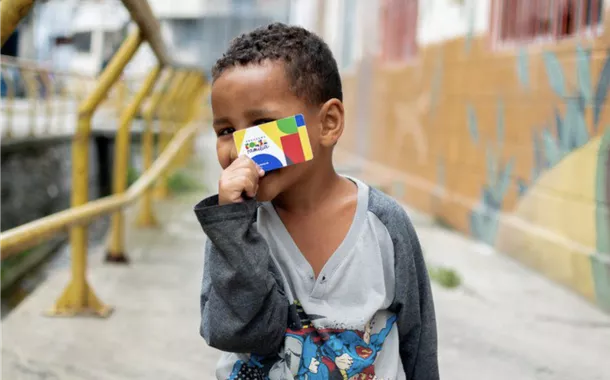 Criança com cartão do Bolsa Família