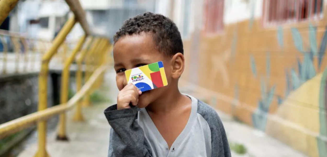 Criança com cartão do Bolsa Família