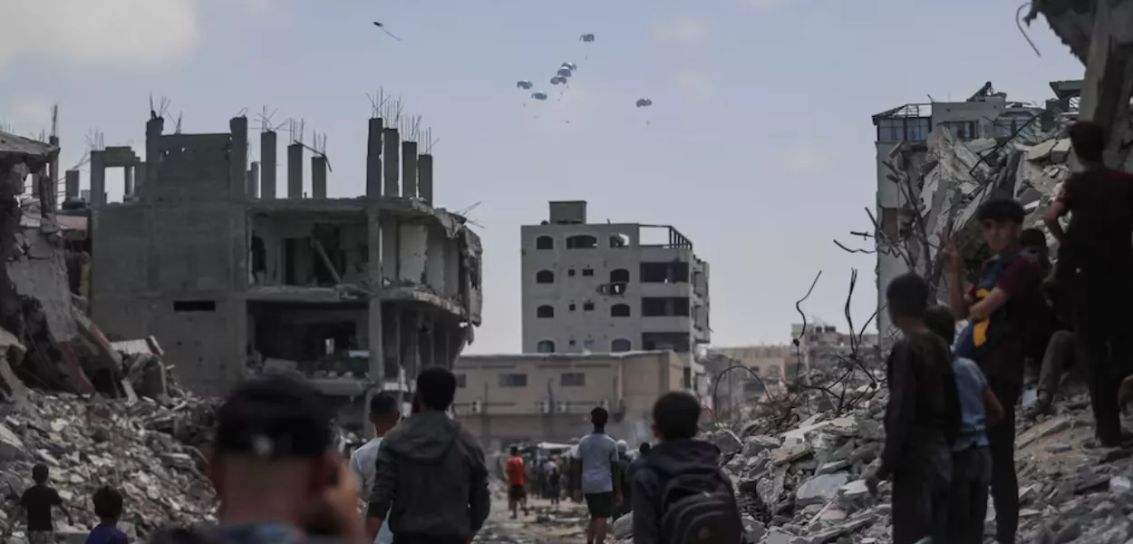 Palestinos observam pacotes de ajuda lançados de avião sobre Gaza, na Cidade de Gaza