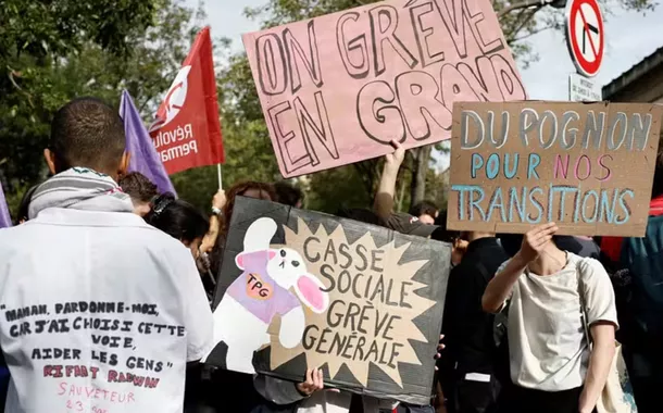 Manifestantes seguram cartazes enquanto se reúnem em frente ao hospital Tenon durante um dia de protestos em Paris