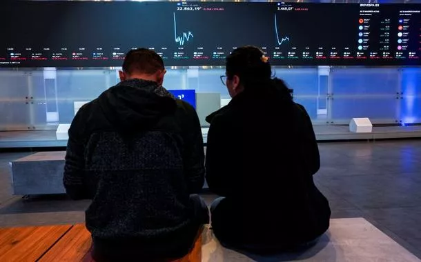 Pessoas observam painéis eletrîonicos na B3, em São Paulo