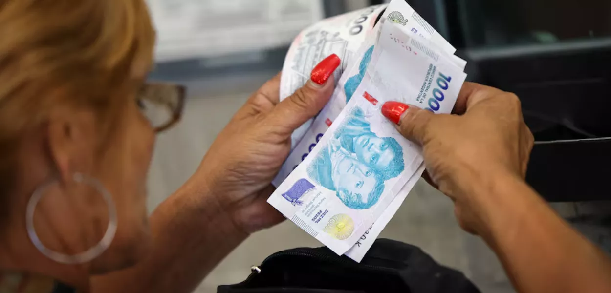 Um cliente conta notas de peso argentino antes de pagar em um supermercado, em Buenos Aires, Argentina, em 13 de janeiro de 2025