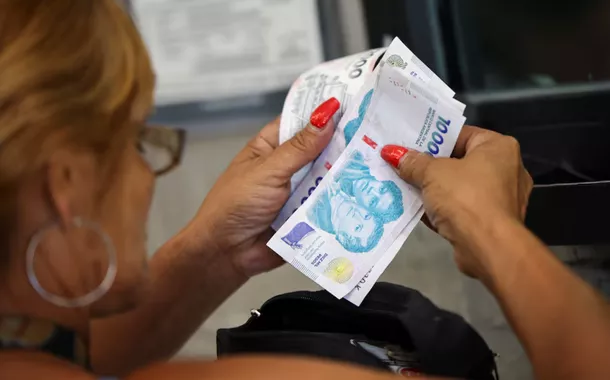 Um cliente conta notas de peso argentino antes de pagar em um supermercado, em Buenos Aires, Argentina, em 13 de janeiro de 2025
