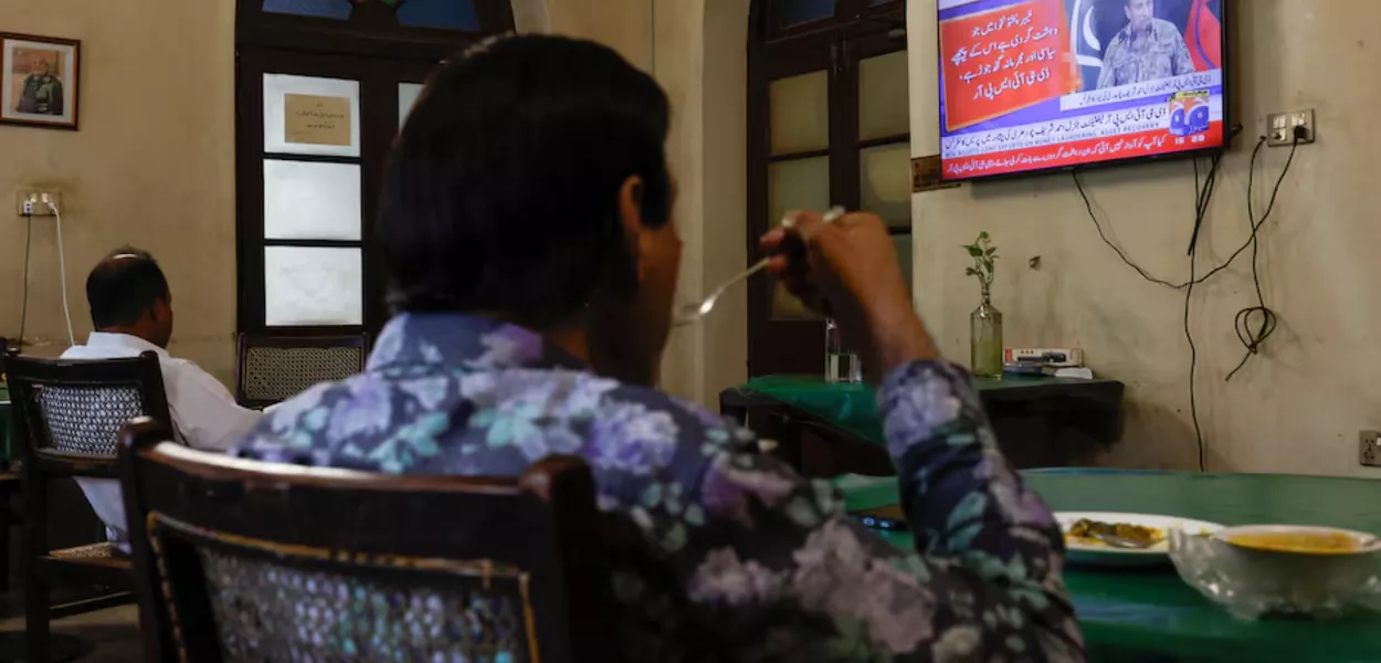 Pessoas assistem a uma coletiva de imprensa televisionada por Ahmed Sharif Chaudhry, Diretor Geral da Divisão de Relações Públicas Inter-Serviços das Forças Armadas do Paquistão, em Karachi, Paquistão, em 10 de outubro de 2025