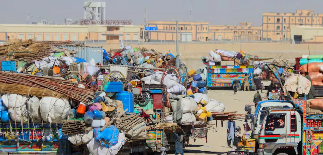 Pessoas passam por veículos estacionados com pertences de cidadãos afegãos, enquanto retornam ao seu país, depois que o Paquistão fechou as passagens de fronteira com o Afeganistão, após trocas de tiros entre as forças dos dois países em Chaman, a passagem de fronteira ao longo da fronteira Paquistão-Afeganistão na província de Baluchistão, em Chaman, Paquistão, 12 de outubro de 2025