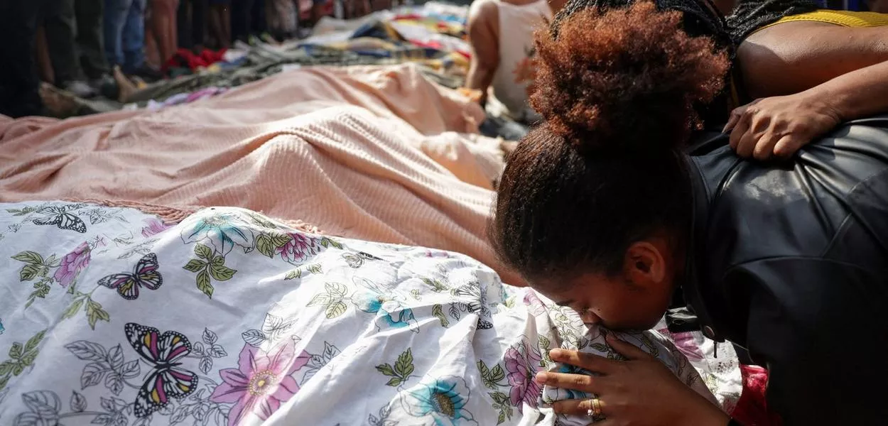 Mulher beija corpo coberto com um lençol após operação policial que deixou ao menos 119 mortos no Rio de Janeiro - 29/10/2025 