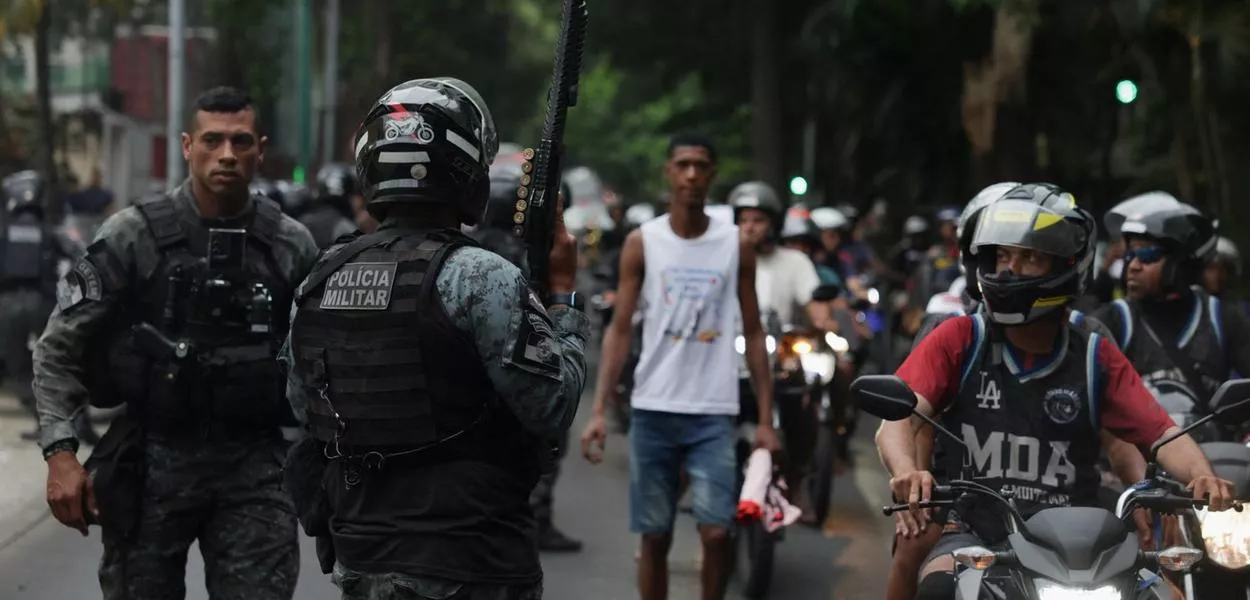 Policial segura arma enquanto moradores dos complexos do Alemão e da Penha protestam do lado de fora da sede do governo do estado do Rio de Janeiro, após a chacina policial que matou ao menos 121 pessoas - 29/10/2025
