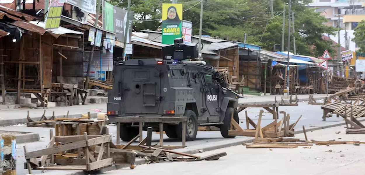 Veículo da polícia tanzaniana trafega por uma estrada bloqueada por manifestantes durante os violentos protestos que marcaram as eleições