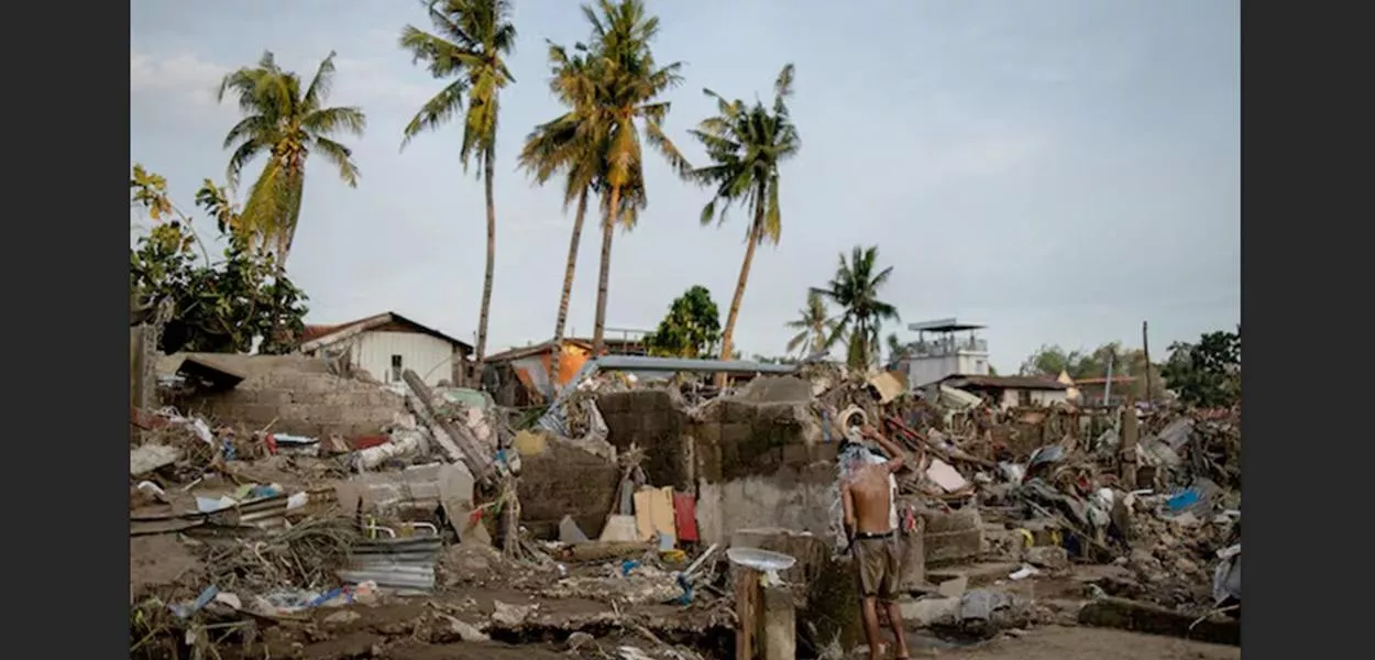 Um homem toma banho entre os destroços de uma comunidade onde as casas foram arrastadas pelas enchentes causadas pelo tufão Kalmaegi, em Talisay, Cebu, nas Filipinas