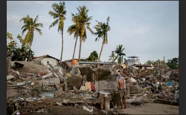 Um homem toma banho entre os destroços de uma comunidade onde as casas foram arrastadas pelas enchentes causadas pelo tufão Kalmaegi, em Talisay, Cebu, nas Filipinas