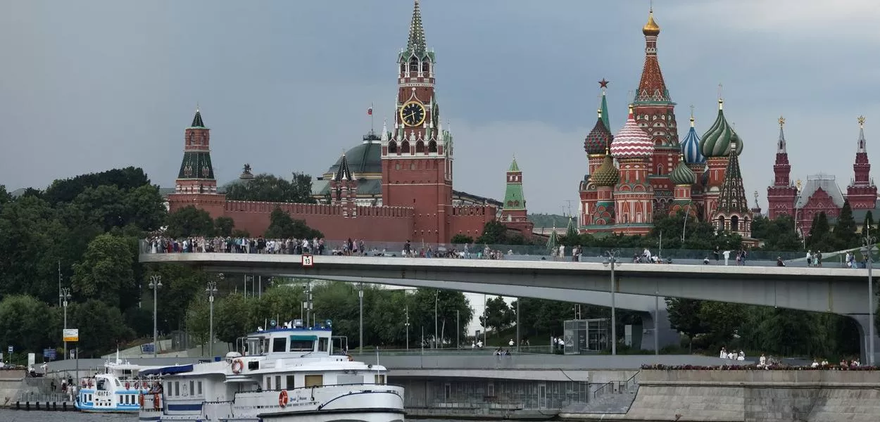 Embarcação navega pelo rio Moscou com a Torre Spasskaya do Kremlin e a Catedral de São Basílio ao fundo - 14 de julho de 2025