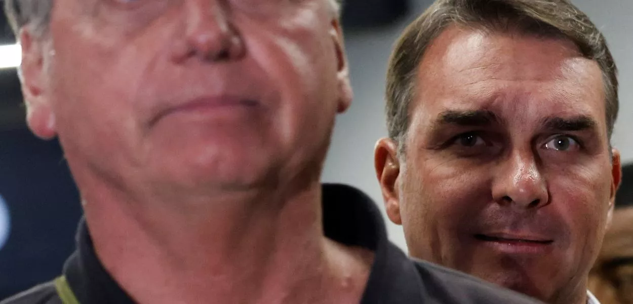 O senador Flávio Bolsonaro observa o pai, o ex-presidente Jair Bolsonaro, no Aeroporto Internacional de Brasília - 25/11/2024