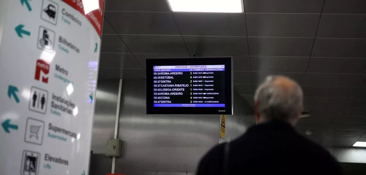 Homem olha para tela que marca partidas de trens na estação de Entrecampos, em Lisboa, em meio a greve geral no país