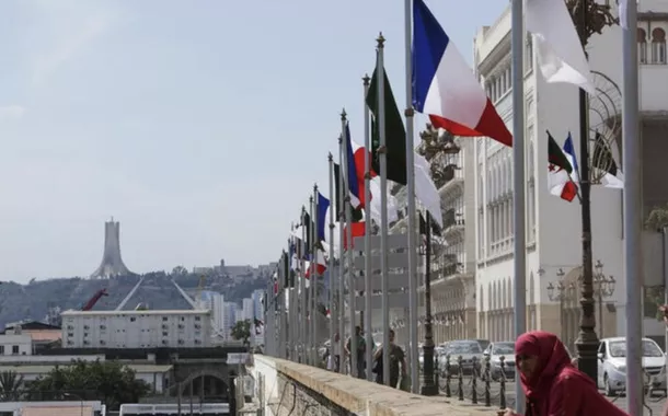 Uma mulher permanece próxima às bandeiras da Argélia e da França antes da chegada do presidente francês, Emmanuel Macron, a Argel para uma visita oficial, em 25 de agosto de 2022