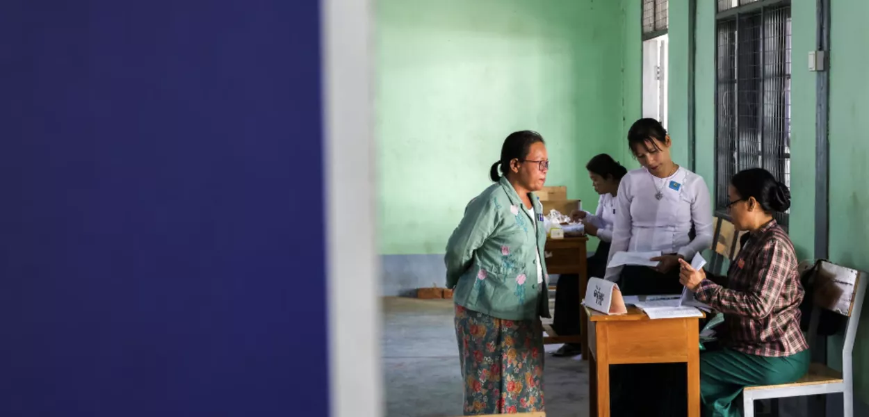 Funcionários da Comissão Eleitoral se preparam em uma seção eleitoral dentro de uma escola, antes das eleições gerais, no município de Thingangyun, Yangon, Mianmar, em 27 de dezembro de 2025